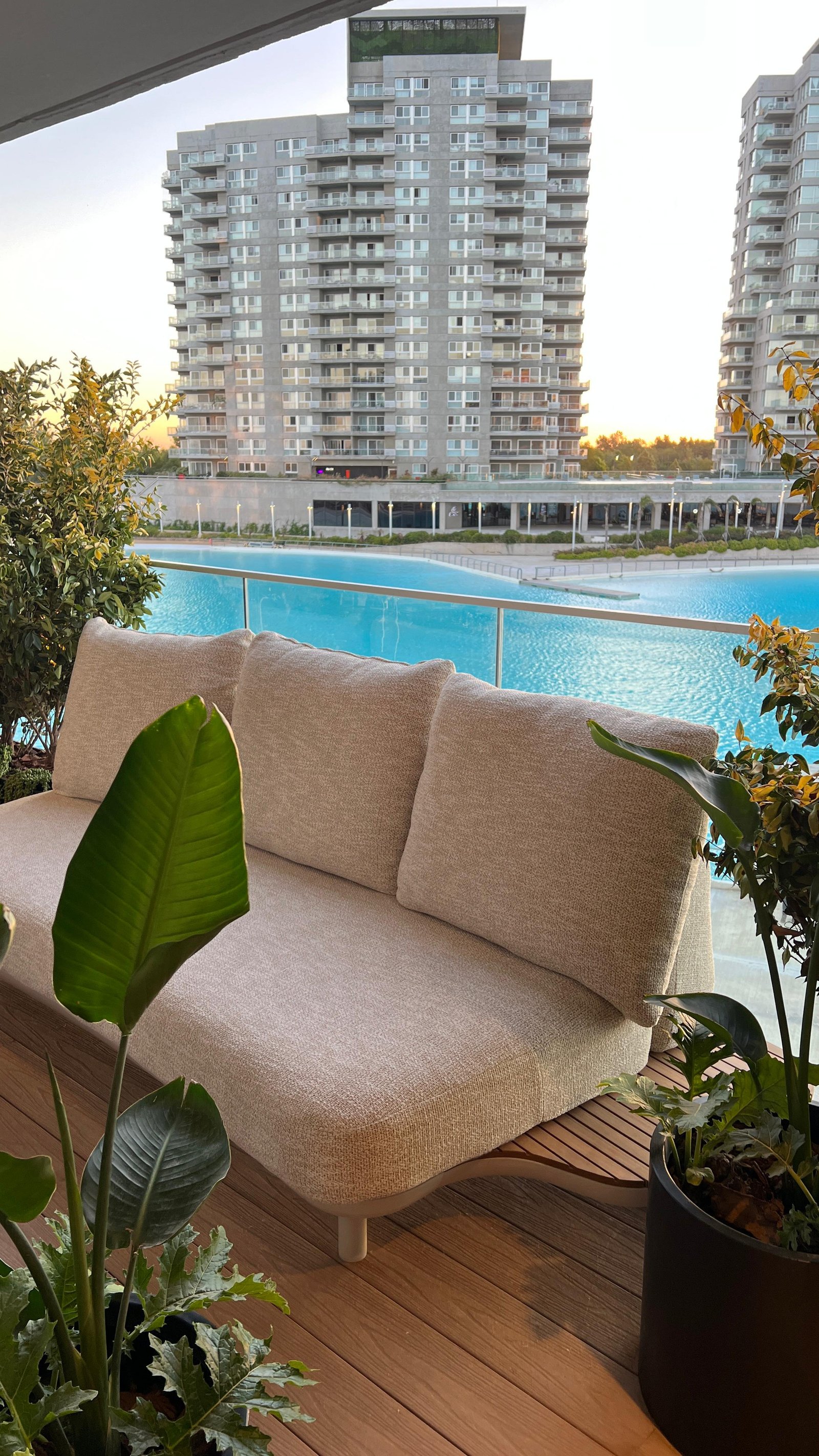 Sofá moderno en balcón con vista a piscina y edificios — proyecto EXPERIENCIA LIVING 26, por DESDE ASIA, en Cam. de los Remeros 1585